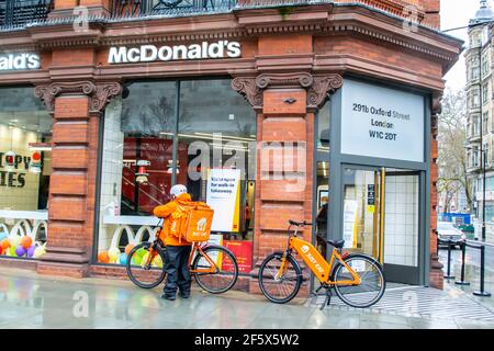 OXFORD STREET, LONDRA, INGHILTERRA - 17 febbraio 2021: McDonald's con biciclette da mangiare appena e un autista di consegna all'esterno, in mezzo all'ultima serratura del coronavirus Foto Stock