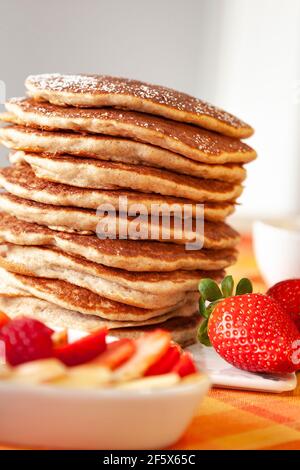 Frittelle torre con zucchero in polvere e frutta. Fragole, mele, noci e marmellata. Foto Stock