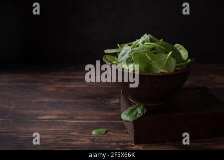 Ciotola con spinaci su fondo di legno scuro, alimentazione sana, stile rustico, primo piano. Foto Stock