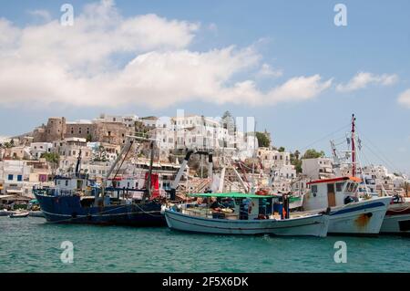 Barche da pesca ancorate nel vecchio porto dell'isola di Naxos in Grecia. Sullo sfondo vi sono il castello, la città e il cielo parzialmente nuvoloso. Foto Stock