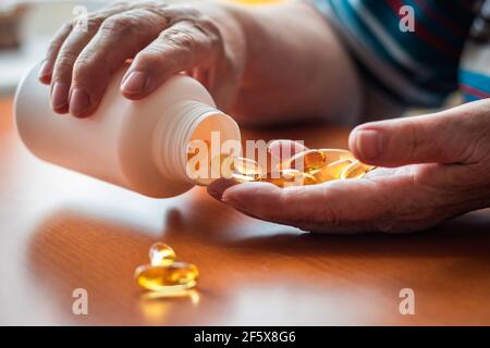 La donna anziana adulta sta prendendo omega-3 vitamina supplemento capsula. Bottiglia femminile con olio di pesce. Foto Stock