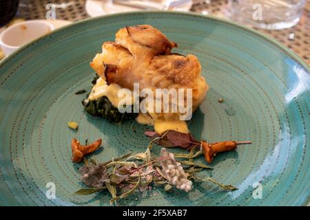 Merluzzo arrosto con spinaci ed erbe su una ceramica verde piastra Foto Stock