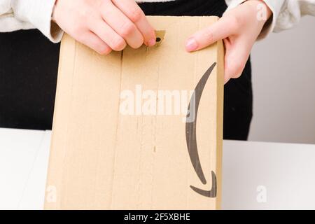 Primo piano mani donna apertura di un pacco da Amazon, marzo 2021, Praga, Repubblica Ceca Foto Stock