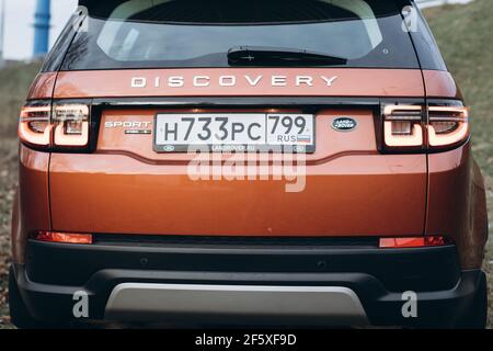 Mosca, Russia - 20 dicembre 2019: Vista posteriore di tutti i nuovi suv premium dell'inghilterra. Land rover Discovery sport parcheggiato nella foresta. Auto a trazione integrale arancione con montante a terra. Foto Stock