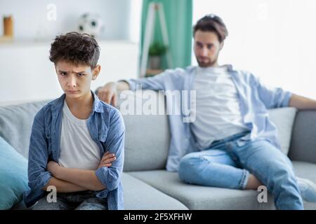 Le generazioni familiari sono in conflitto. Ragazzo e padre sconvolto che non parlano dopo la disputa, figlio e papà seduti sul divano separatamente Foto Stock