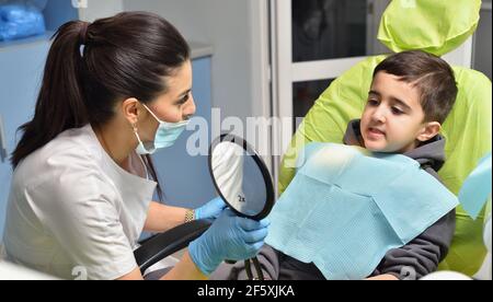 Il bambino al dentista nella sedia mostra il suo denti nello specchio Foto  stock - Alamy