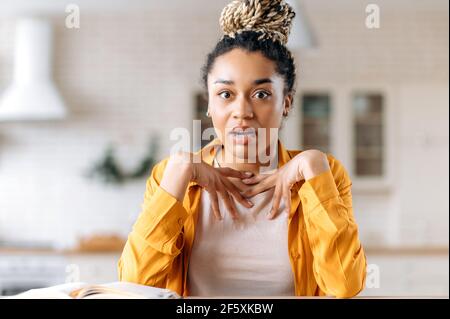 Scioccato stupito giovane donna d'affari afroamericana o freelancer che lavora da casa, chattando con il socio di affari o il capo da video conferenza, sorprende guarda la macchina fotografica, gesturing con le mani Foto Stock