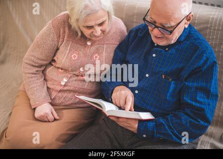 Coppie anziane che leggono la bibbia e pregano insieme a casa. Foto Stock