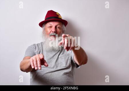 Un vecchio maschio americano con camicia grigia e fedora rossa cappello che si diverte di una persona o di una circostanza Foto Stock