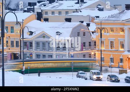 Helsinki, Finlandia - 13 gennaio 2021: Il tram si muove sulla piazza del Senato durante la forte tempesta di neve. L'edificio blu e' il Museo della Citta' di Helsinki Foto Stock