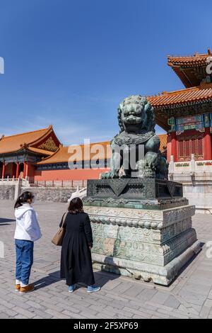 I turisti osservano il leone imperiale di bronzo dell'era Ming iat la Città Proibita a Pechino, Cina nel marzo 2018. Foto Stock