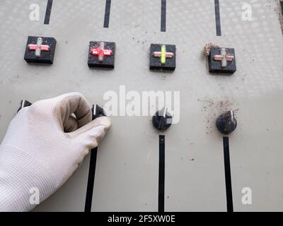 Il guanto del lavoratore della fabbrica ha disattivato un pulsante nero sulla scheda di controllo. Sala tecnica elettrica di vecchia moda. Foto Stock