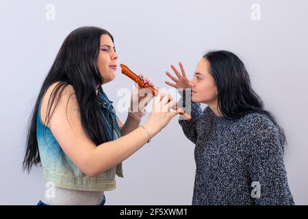 due ragazze attraenti che si divertono con flauto di legno isolato su sfondo chiaro Foto Stock