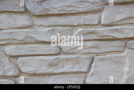 Struttura di un muro di pietra da lunghe e pietre di diverse dimensioni. Parete di pietra lunga grigia Foto Stock