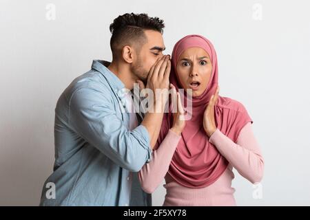 Grande segreto. Il Guy arabo gossiping con la sua ragazza musulmana scioccata a Hijab Foto Stock