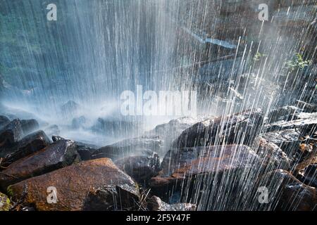 Sparato da dietro la cascata che si schiantano su Rocks Backlit Abstract Foto Stock