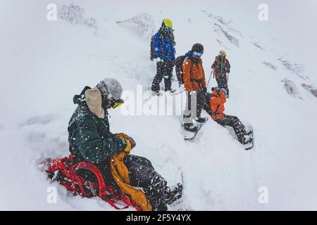 Persone con snowboard sul pendio di montagna innevata durante la nevicata Foto Stock