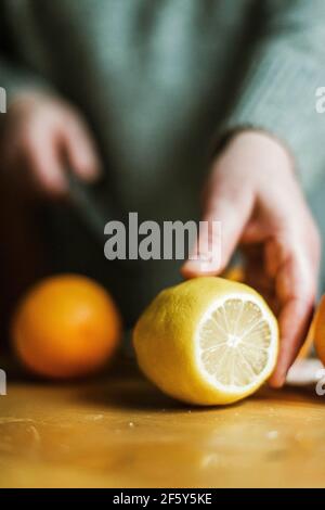 Donna anonima nella sua cucina a casa affettando arance con un sh Foto Stock