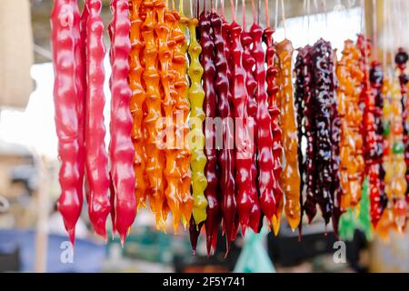 Colorati dolci fatti in casa Churchkhela con nocciole, noci, succo d'uva, miele o zucchero, farina di grano o mais. Dessert venduto nel mercato alimentare locale. Foto Stock