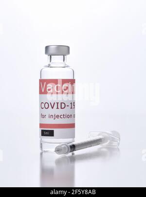 Chiusura di un flaconcino di vaccino Covid-19 e di una siringa su bianco. Foto Stock