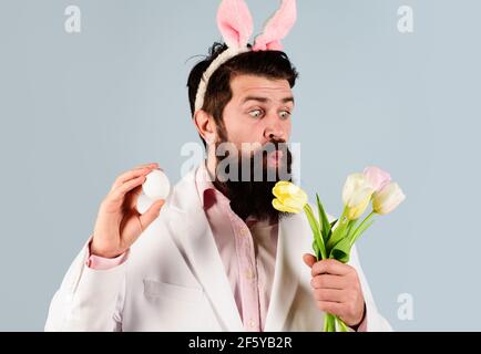 Concetto di celebrazione pasquale. L'uomo sorprendo in costume con uova e fiori. Caccia alle uova. Foto Stock