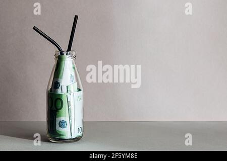 Bottiglia creativa di composizione minimalistica con un cocktail di banconote da 100 euro. Concetto di consumo consapevole, stile di vita sostenibile. Foto Stock