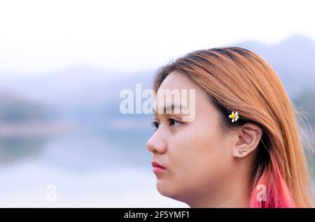 Teenager asiatico con coloratissimi capelli sullo sfondo del lago. Felicità e essere voi stessi concetto. Foto Stock