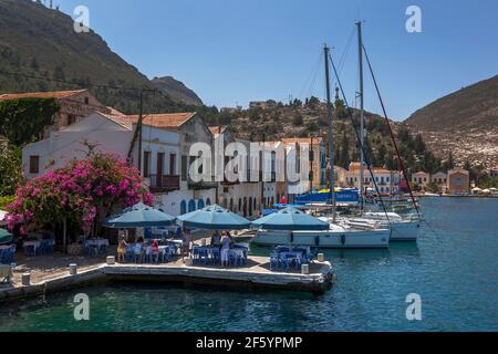 I turisti si siedono in un ristorante sul porto sull'isola di Kastellorizo (Meis) in Grecia. L'isola si trova a 2 chilometri dalla Turchia. Foto Stock