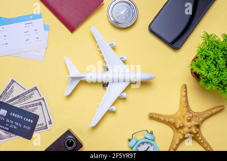 Disposizione degli accessori da viaggio su sfondo giallo. Concetto di viaggio, vacanza e viaggio aereo. Vista dall'alto. Foto Stock