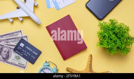 Disposizione degli accessori da viaggio su sfondo giallo. Concetto di viaggio, vacanza e viaggio aereo. Vista dall'alto. Foto Stock