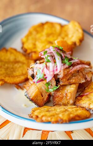 un piatto di piantana fritta servito con manzo grattugiato a gocce con ravvivatura di cipolla e lime Foto Stock