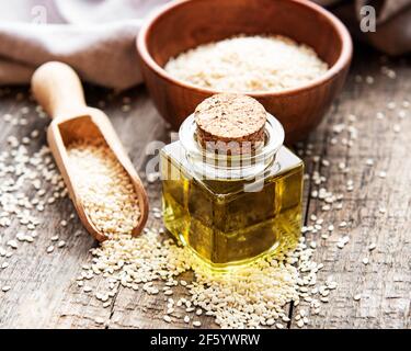 Concetto sano di cibo e bevande. Olio di sesamo e semi su una tavola rustica. Foto Stock