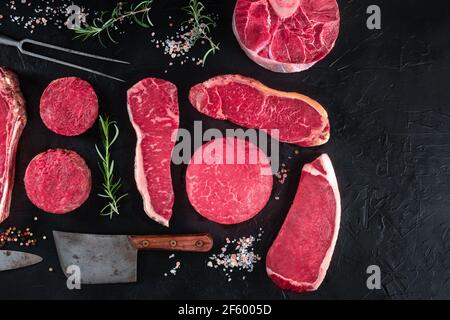 Tagli di carne, una varietà di bistecche di manzo, sparati dall'alto su uno sfondo nero Foto Stock