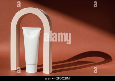 Piedistallo da tavolo con esposizione ad arco art deco e crema per la cura della pelle. Arco geometrico di moda per la presentazione del prodotto, lozione, idratante. Minimo Foto Stock
