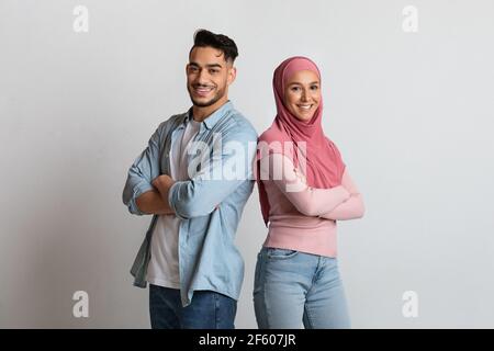 Felice coppia islamica fiduciosa in piedi indietro con ripiegata braccia Foto Stock