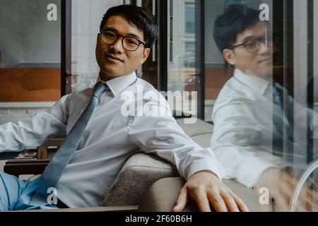 Ritratto di uomo d'affari seduto sul divano in ufficio Foto Stock