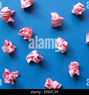 Palline di carta rosa sbriciolati su sfondo blu. Concetto di idea creativa Foto Stock