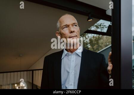 Uomo d'affari anziano che guarda via all'ufficio Foto Stock