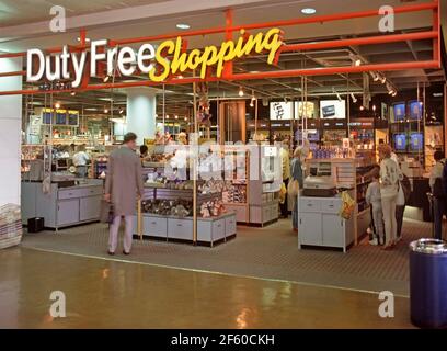 La storica vista d'archivio del 1987 sull'insegna illuminata del negozio sopra i negozi Duty Free mostra il design di un negozio interno di una sala partenze degli anni '80 all'interno dell'edificio con gli acquirenti in viaggio che curiosano tra le marche di merci prima di volare dall'aeroporto di Gatwick West Sussex Inghilterra Regno Unito un'immagine d'archivio del modo in cui eravamo negli anni '1980 Foto Stock