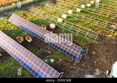 Vista aerea della centrale solare in costruzione su campo verde. Assemblaggio di quadri elettrici per produrre energia ecologica pulita. Foto Stock