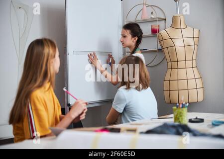 Ragazze carine che discutono il processo di dressmaking in officina di cucitura Foto Stock