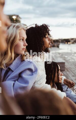 Le amiche che guardano mentre si siedono sul molo Foto Stock