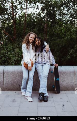 Ritratto di amici femminili con braccio attorno appoggiato sul ritegno parete sul sentiero Foto Stock