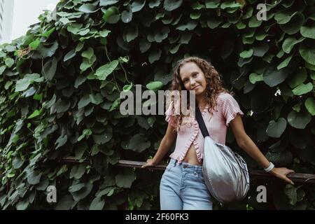 Ritratto di donna che pende su ringhiera contro le piante Foto Stock