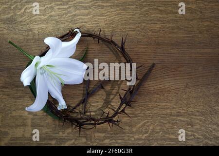 Venerdì Santo, Passione di Gesù Cristo. Corona di spine, chiodi e giglio bianco su sfondo di legno. Festa cristiana di Pasqua. Foto Stock