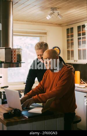 Coppia omosessuale che usa il laptop in cucina a casa Foto Stock