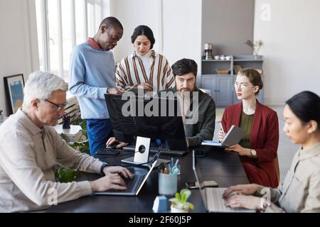 Ritratto di diversi gruppi di uomini d'affari che si incontrano in ufficio e utilizzando il computer durante la discussione del progetto Foto Stock