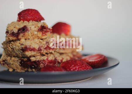 Bar di avena di fragole fatte in casa con fragole fresche e avena arrotolata. Scatto su sfondo bianco Foto Stock