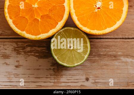 Arance, lime e limoni scivoli su tavola di legno vista da sopra.Beautiful Sfondo con frutta fresca metà cut.Healthy mangiare vitamina C.Summer tropic Foto Stock