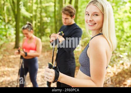 Giovane donna attiva che fa sport nordic walking con gli amici in natura Foto Stock